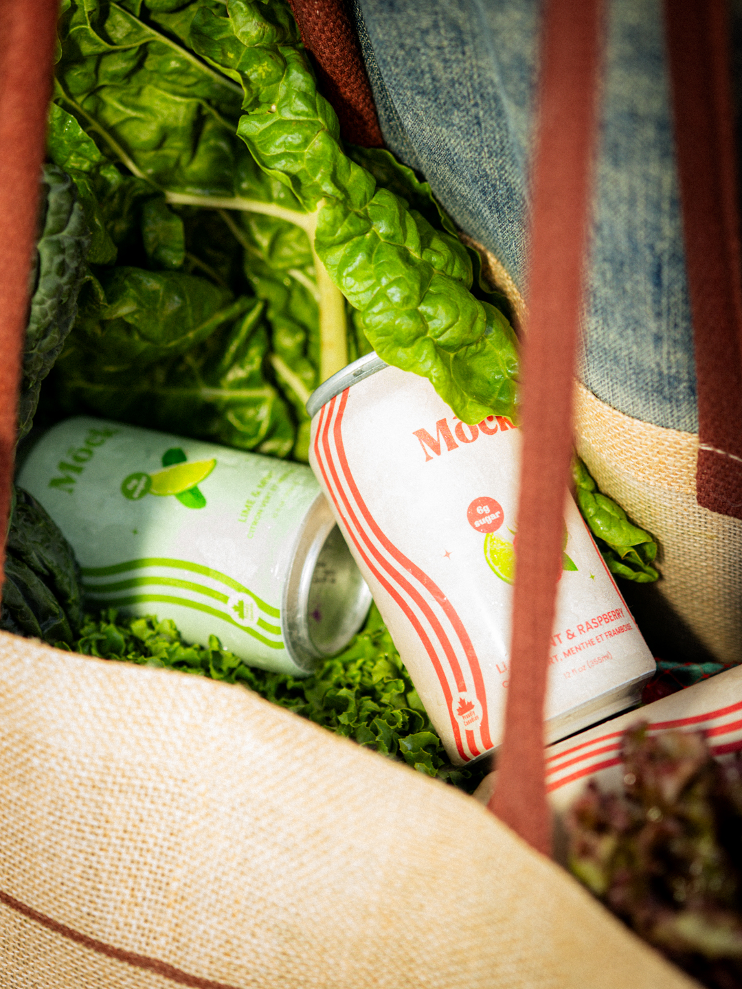 Mōck cans nestled among greens inside a tote